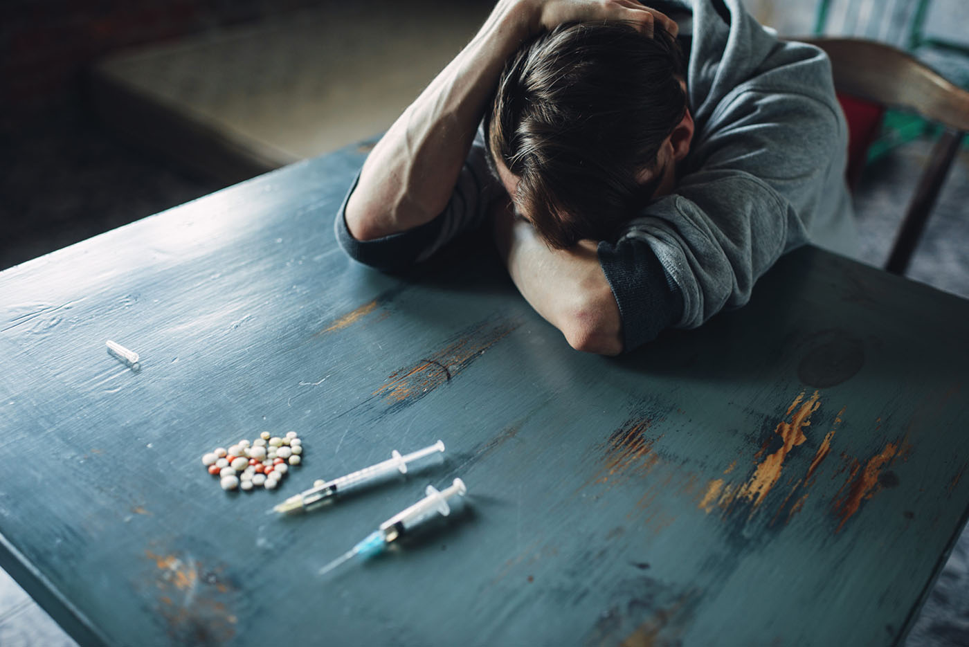 male-junkie-at-the-table-with-drugs-and-syringe-5yh84eu-scaled